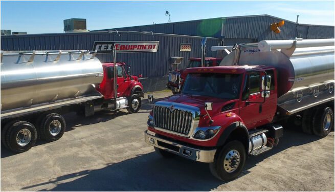 Red semi-trucks are parked at a commercial vehicle service center on a sunny day.