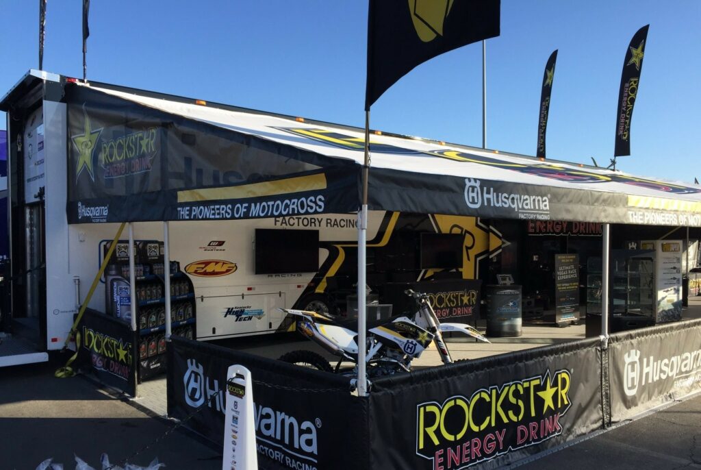 A Rockstar Energy Drink promotional tent with various branding elements and merchandise displayed underneath.