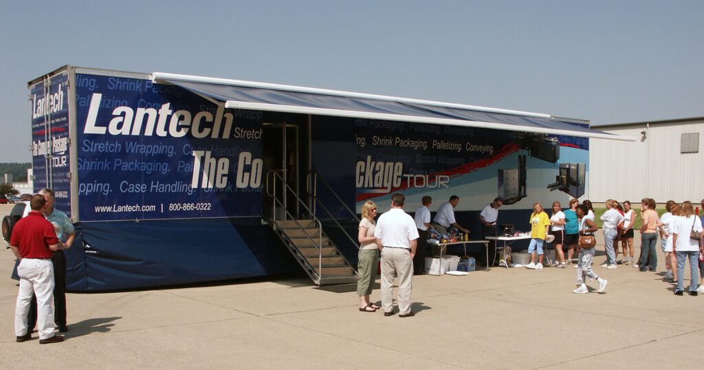 a trailer that has its sunroof up and a few people standing outside of it
