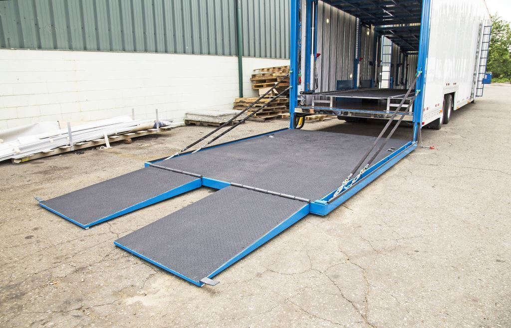 A large metal loading ramp is positioned on the ground outside a warehouse or industrial building.