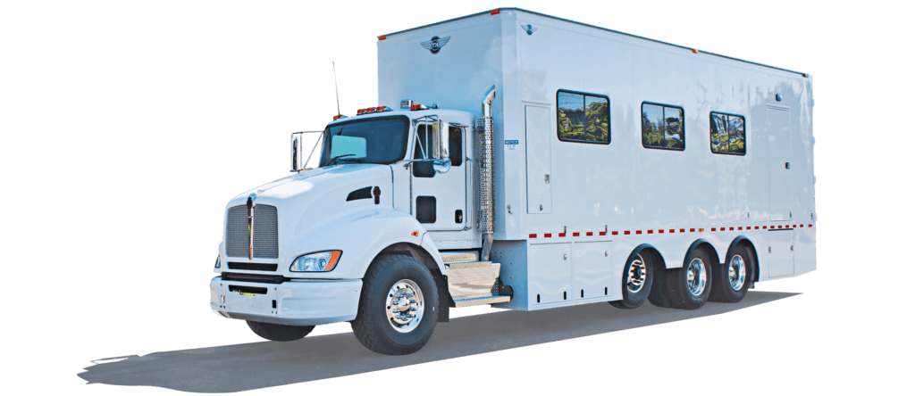 A white semi-truck with an attached large trailer is parked, with part of its side and rear visible against a green background.