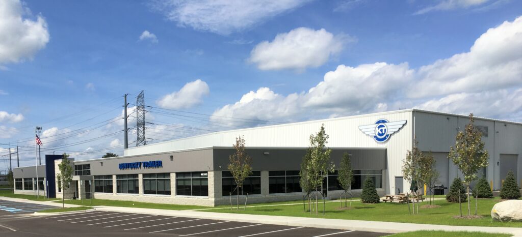 A modern industrial building with the "RA Power Solutions" logo on the side is set against a partly cloudy blue sky.