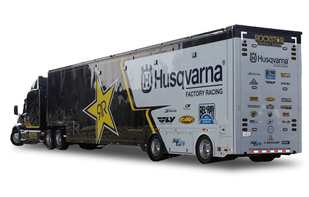 A large white and black racing trailer features the Husqvarna and Rockstar Energy logos along with other sponsor decals.