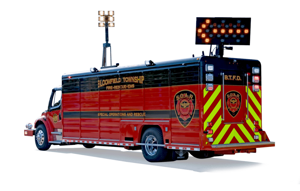 A large red fire department command vehicle is equipped with emergency lights, high-visibility chevrons, and an electronic arrow board sign.